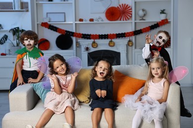 Photo of Funny children wearing costumes for Halloween celebration in room