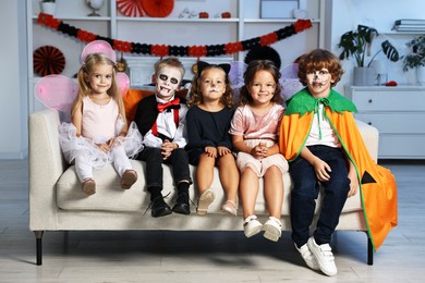 Photo of Funny children wearing costumes for Halloween celebration in room