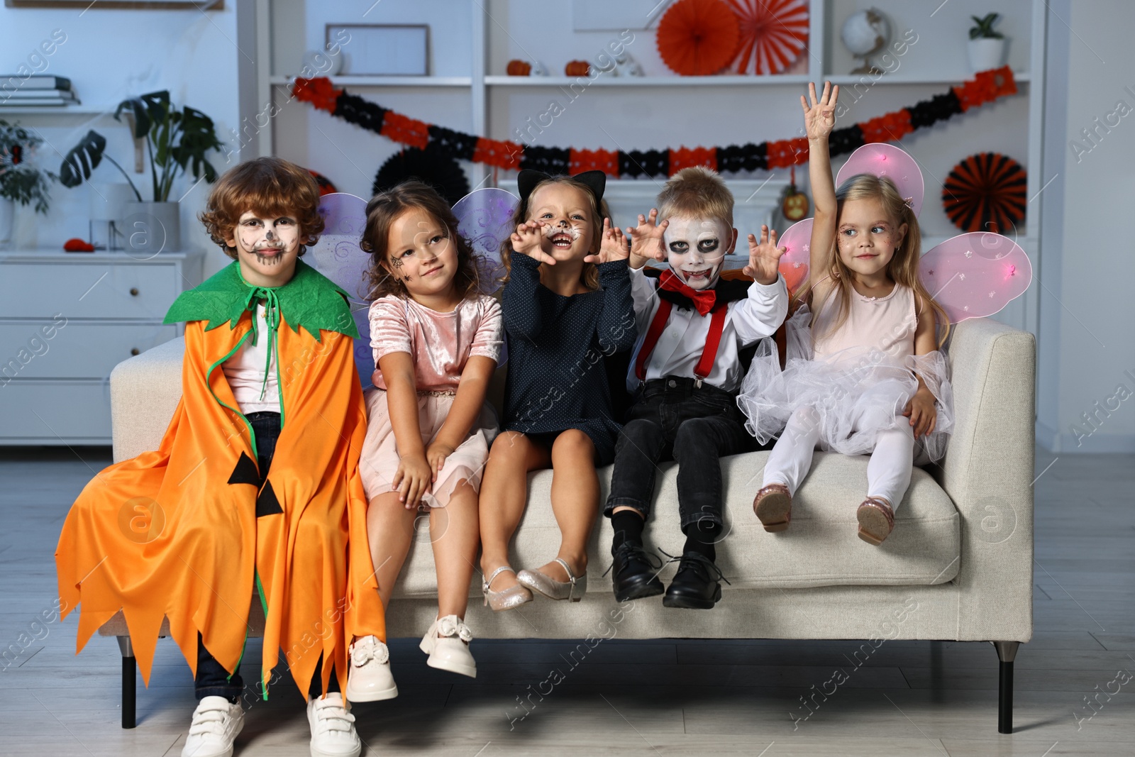 Photo of Funny children wearing costumes for Halloween celebration in room