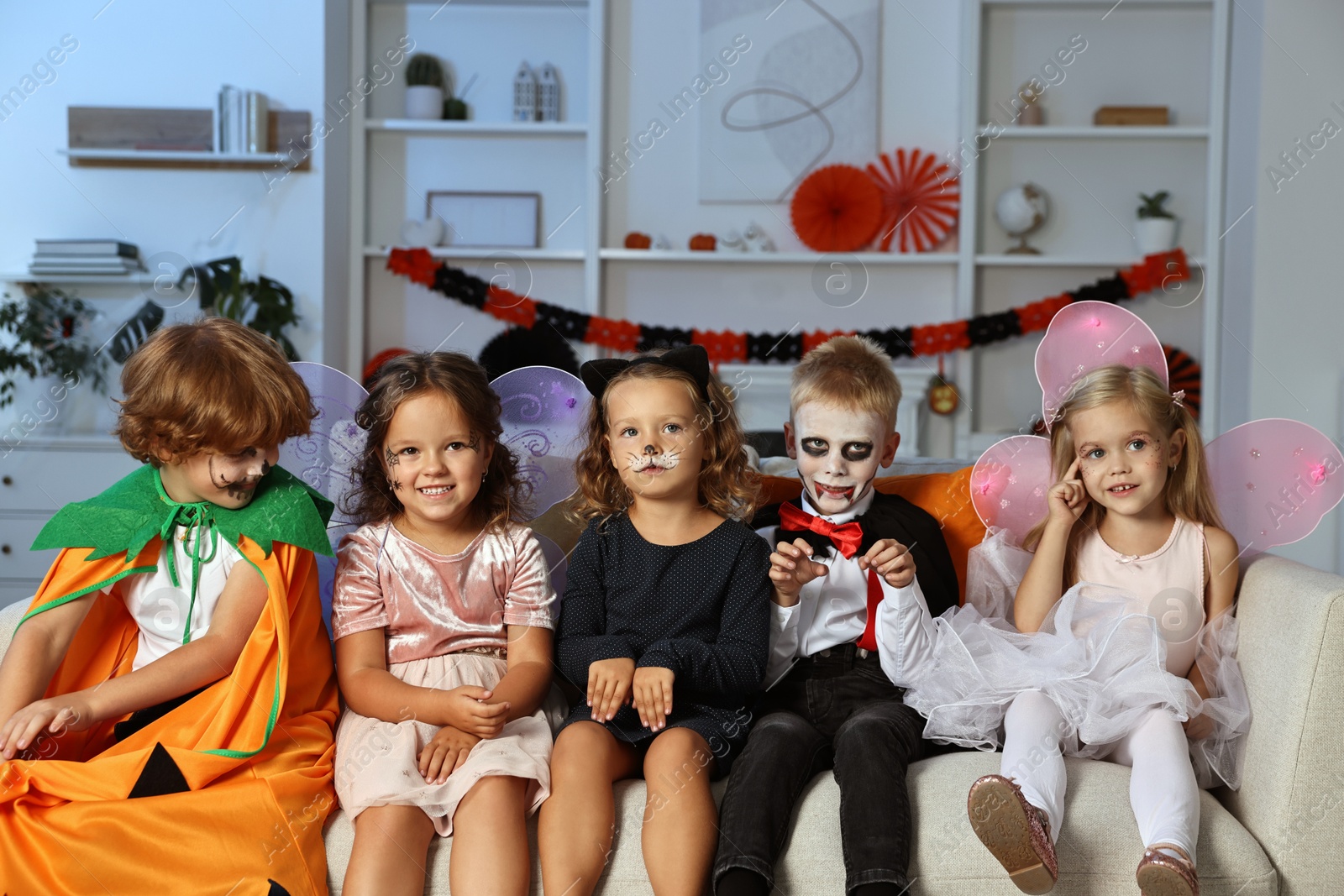 Photo of Funny children wearing costumes for Halloween celebration in room