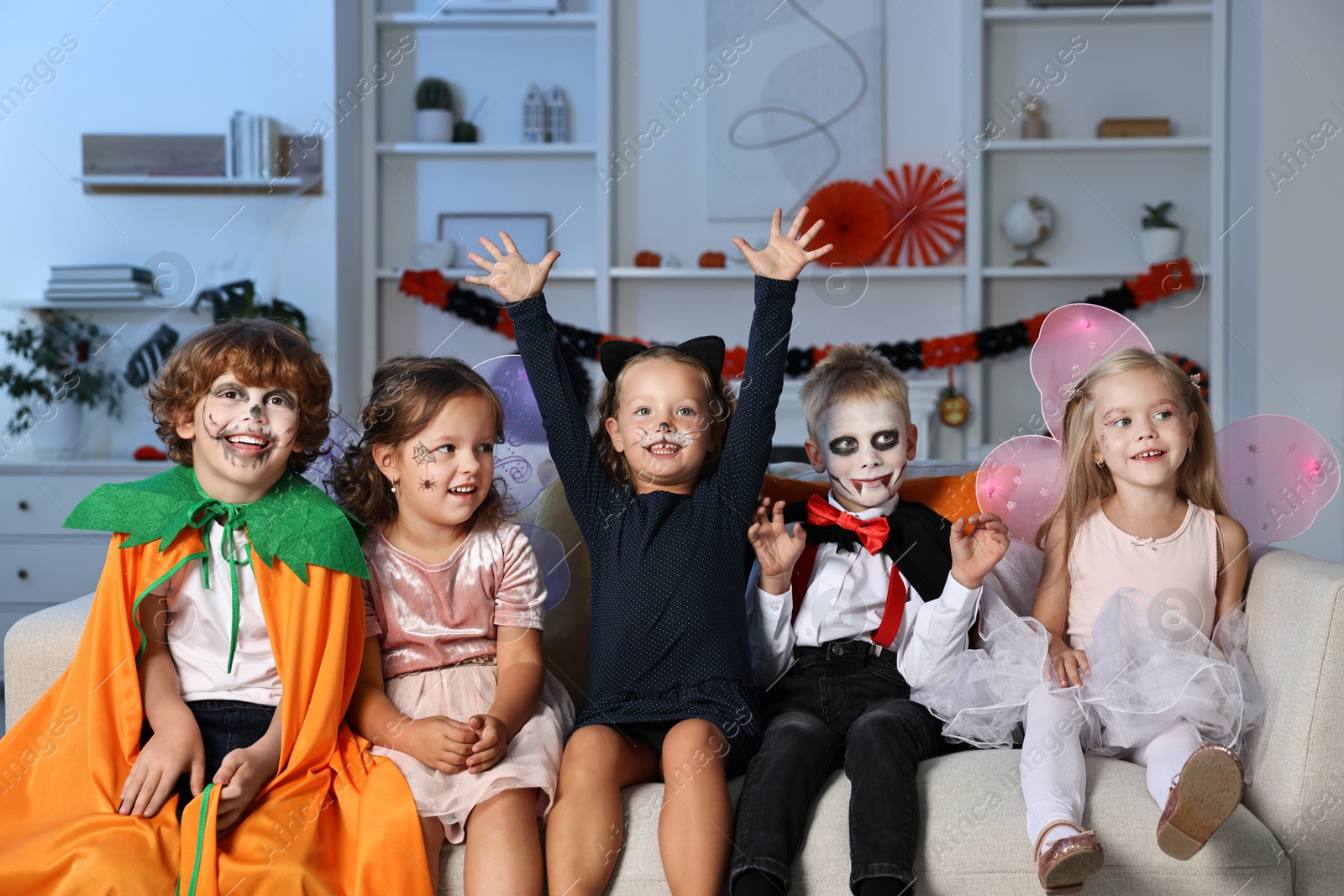 Photo of Funny children wearing costumes for Halloween celebration in room