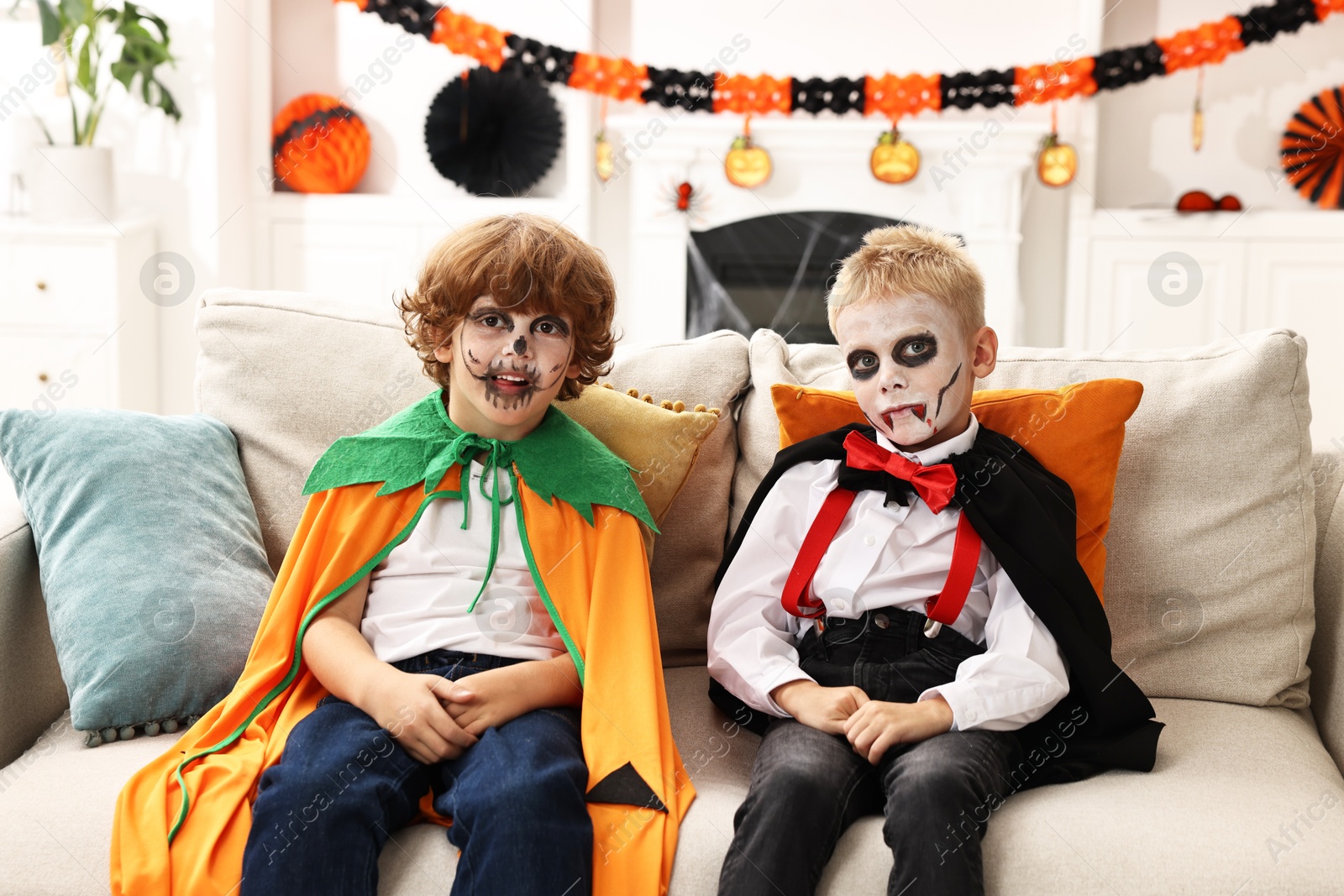 Photo of Funny children wearing costumes for Halloween celebration in room