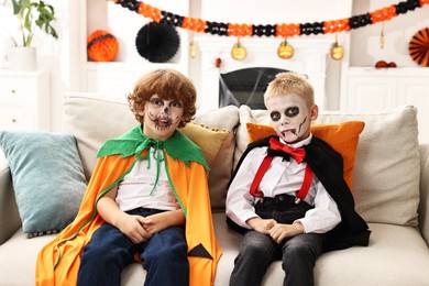 Funny children wearing costumes for Halloween celebration in room