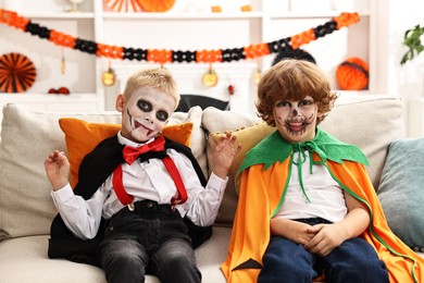 Photo of Funny children wearing costumes for Halloween celebration in room