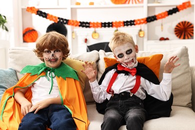 Funny children wearing costumes for Halloween celebration in room