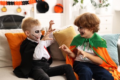 Photo of Funny children wearing costumes for Halloween celebration in room