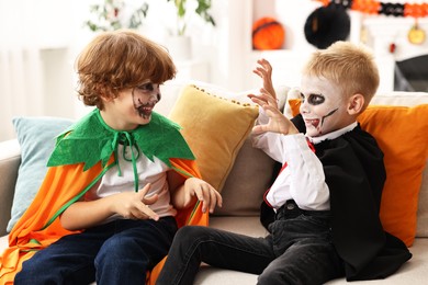 Photo of Funny children wearing costumes for Halloween celebration in room