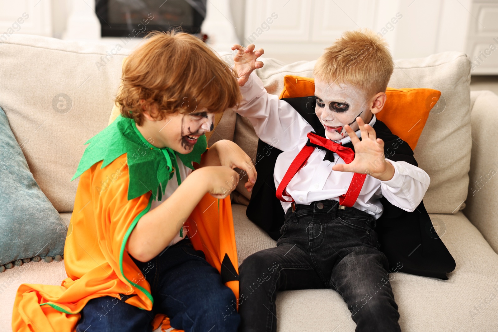 Photo of Funny children wearing costumes for Halloween celebration in room