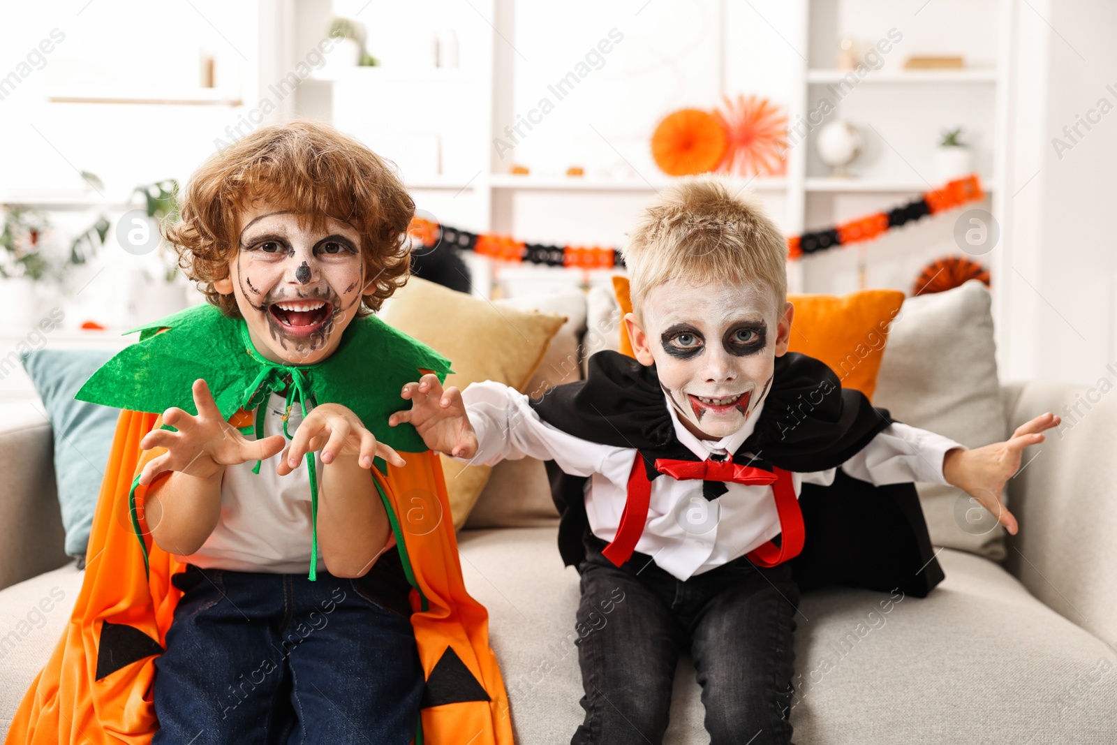 Photo of Funny children wearing costumes for Halloween celebration in room