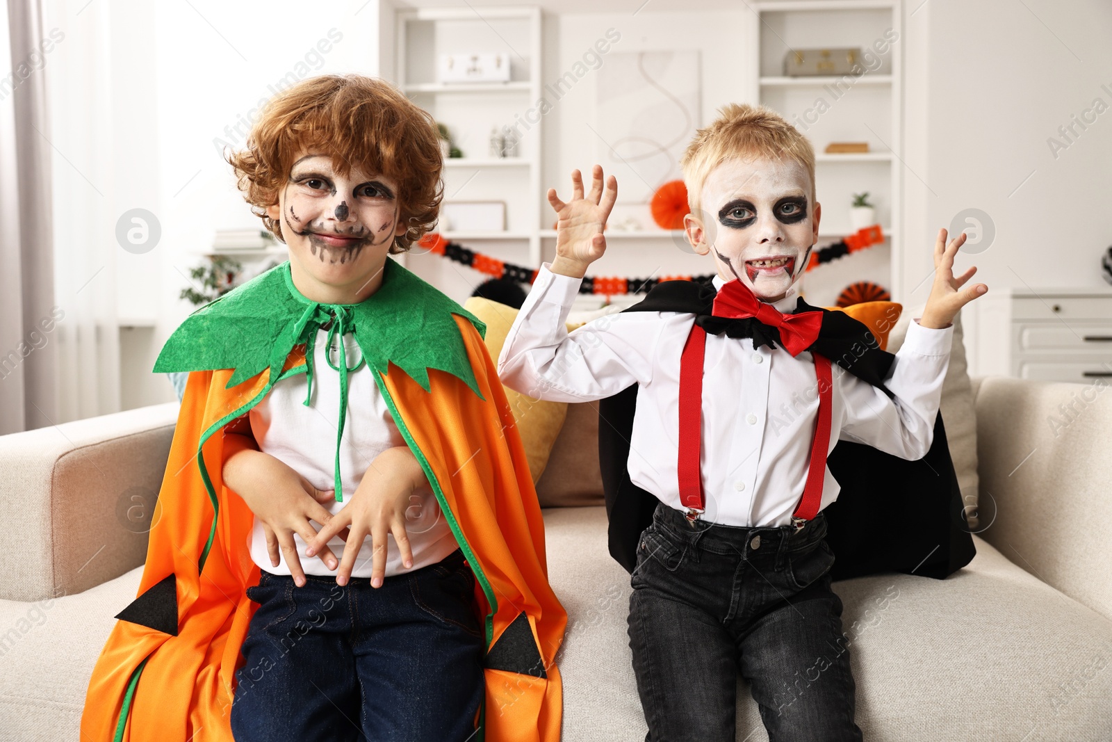 Photo of Funny children wearing costumes for Halloween celebration in room