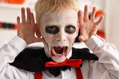 Photo of Funny boy dressed like vampire for Halloween celebration indoors