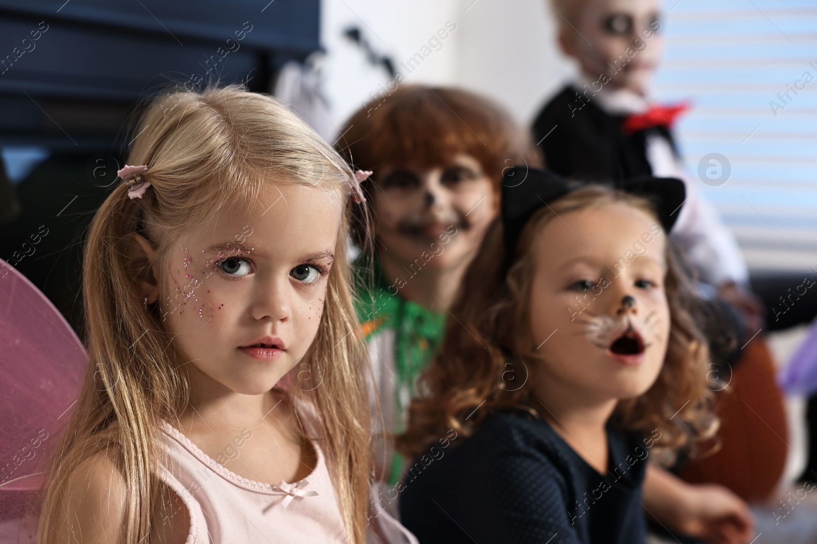 Photo of Funny children wearing costumes for Halloween celebration indoors, selective focus