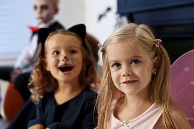 Photo of Funny children wearing costumes for Halloween celebration indoors, selective focus