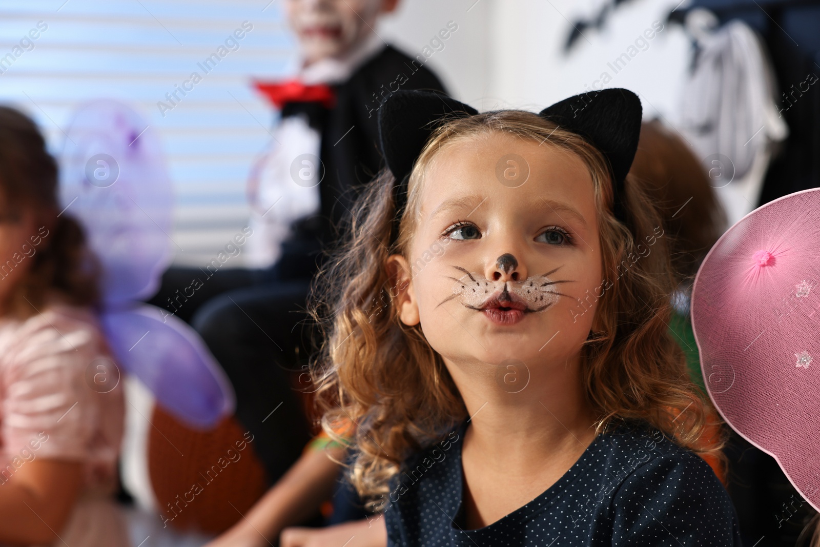 Photo of Funny children wearing costumes for Halloween celebration indoors, selective focus