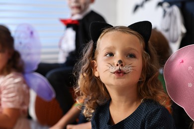 Photo of Funny children wearing costumes for Halloween celebration indoors, selective focus