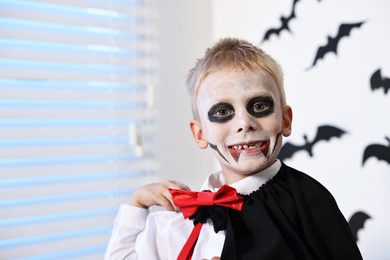 Photo of Funny boy dressed like vampire for Halloween celebration indoors