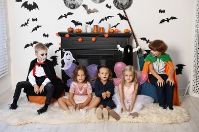 Funny children wearing costumes for Halloween celebration in decorated room