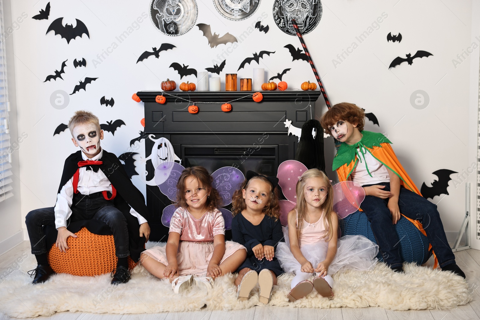 Photo of Funny children wearing costumes for Halloween celebration in decorated room