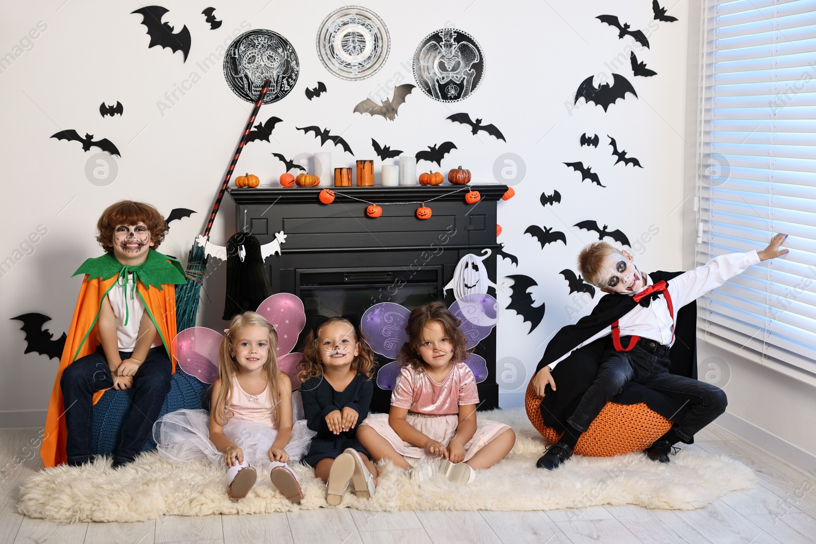 Photo of Funny children in costumes for Halloween celebration in decorated room