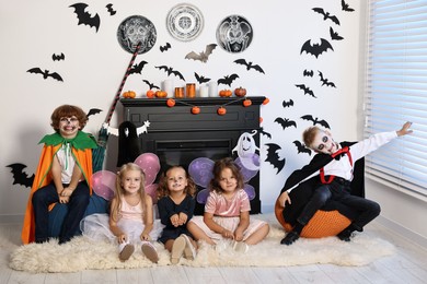 Funny children in costumes for Halloween celebration in decorated room