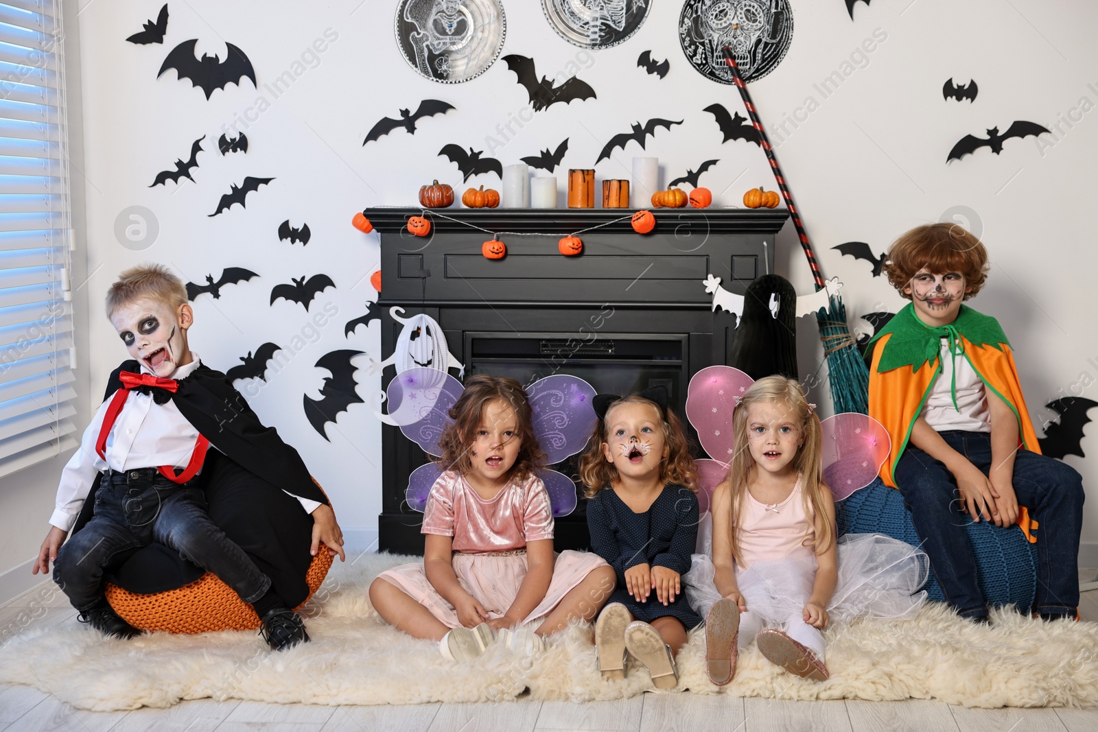 Photo of Funny children wearing costumes for Halloween celebration in decorated room