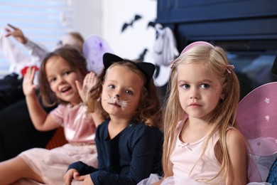 Funny children wearing costumes for Halloween celebration in room, selective focus