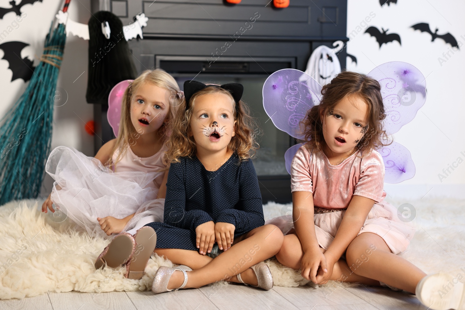 Photo of Cute girls wearing costumes for Halloween celebration in room