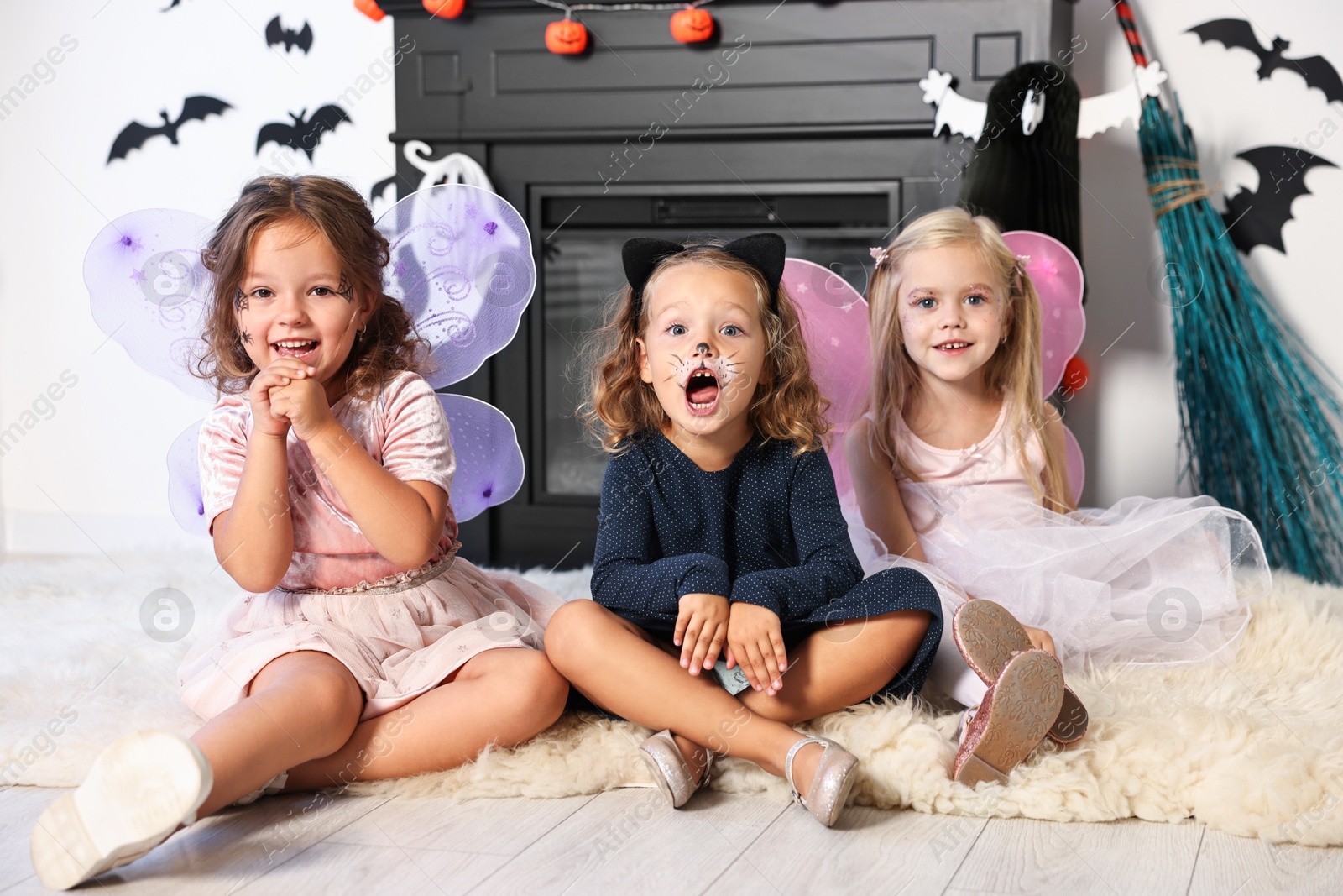 Photo of Cute girls wearing costumes for Halloween celebration in room