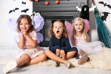 Cute girls wearing costumes for Halloween celebration in room