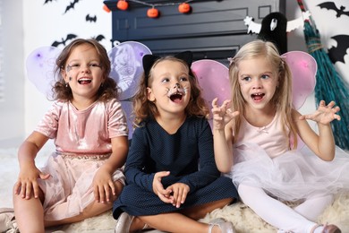 Cute girls wearing costumes for Halloween celebration in room