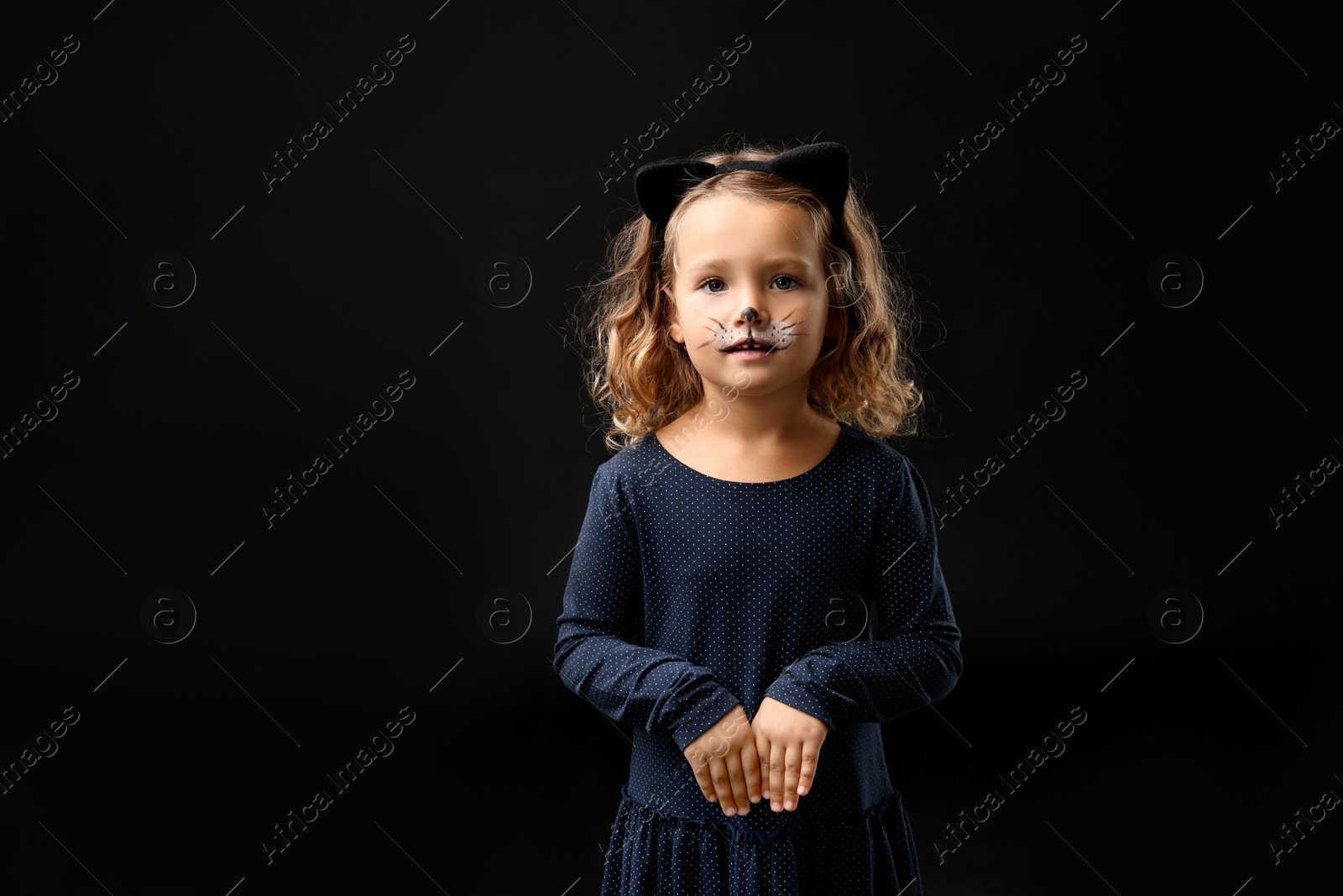 Photo of Funny girl dressed like cat for Halloween celebration on black background