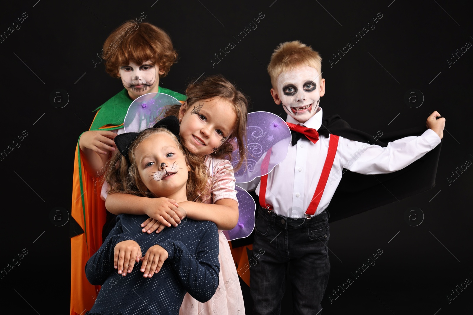 Photo of Funny children wearing costumes for Halloween celebration on black background