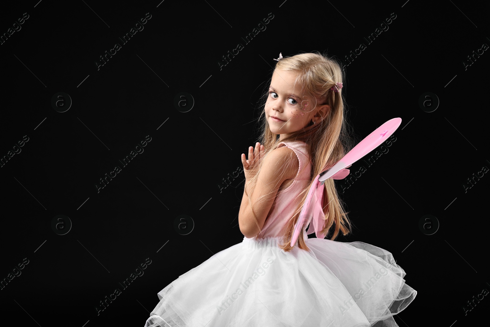 Photo of Cute girl dressed like fairy on black background, space for text. Halloween costume