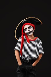 Photo of Funny boy dressed like pirate for Halloween celebration on black background