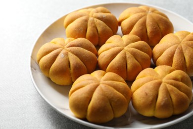 Photo of Tasty pumpkin shaped buns on grey table, closeup