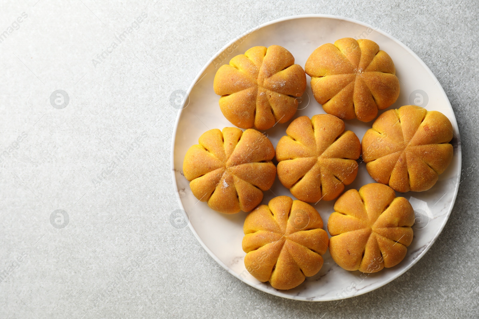 Photo of Tasty pumpkin shaped buns on grey table, top view. Space for text