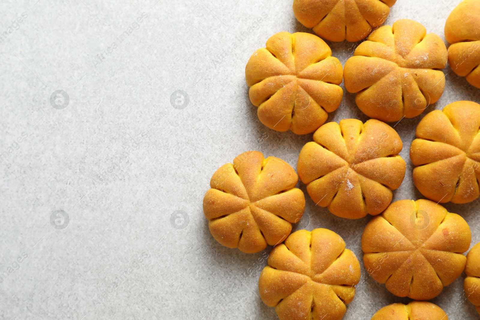 Photo of Tasty pumpkin shaped buns on grey table, flat lay. Space for text