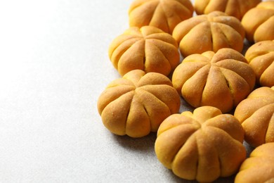 Photo of Tasty pumpkin shaped buns on light table, closeup. Space for text