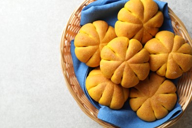 Photo of Wicker basket with tasty pumpkin shaped buns on light table, top view. Space for text