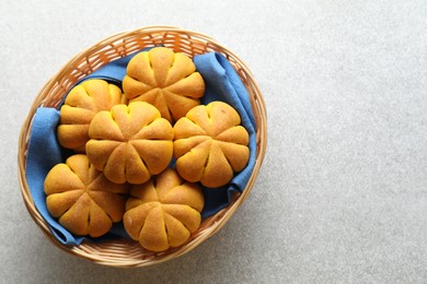 Photo of Wicker basket with tasty pumpkin shaped buns on light table, top view. Space for text