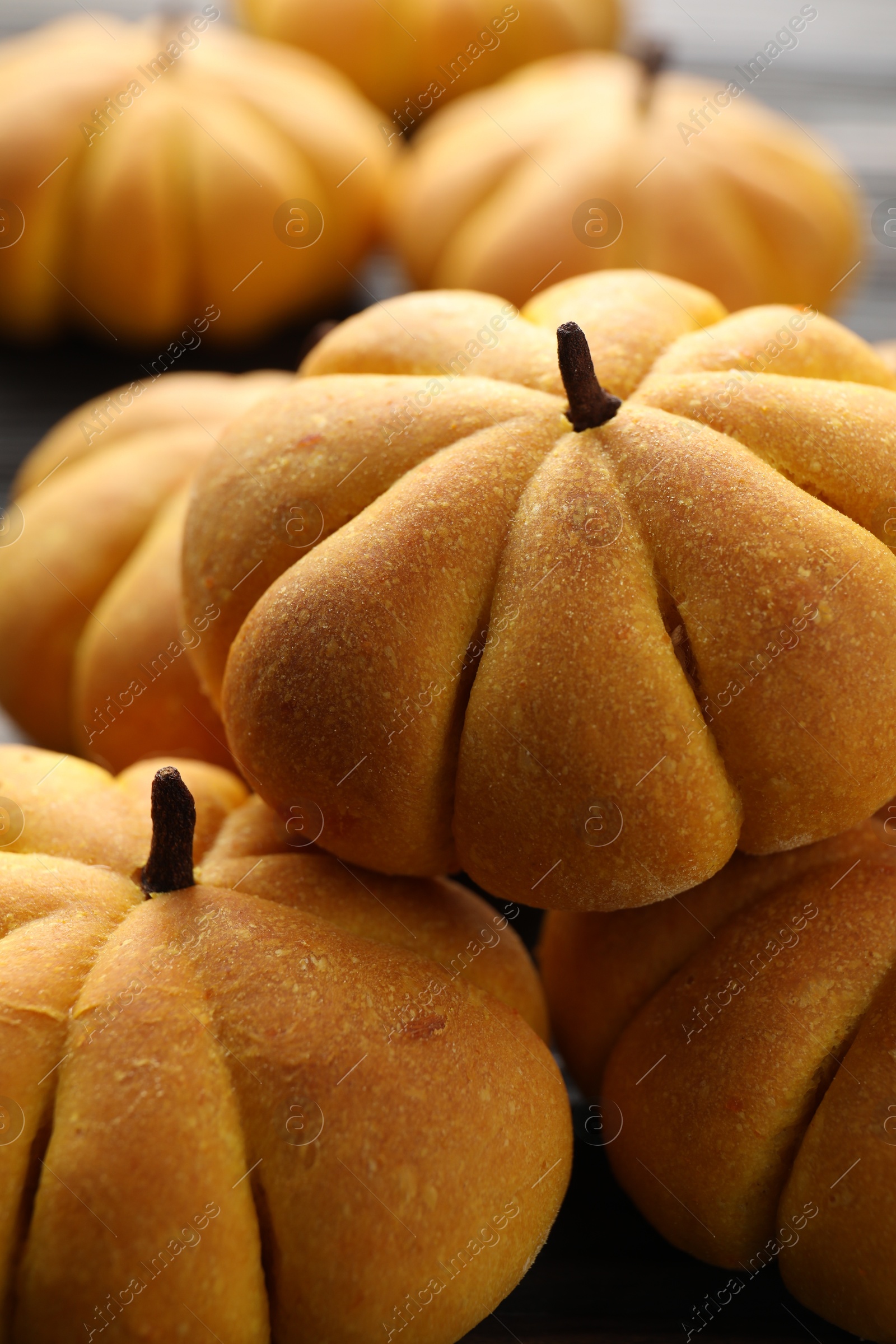 Photo of Pile of tasty pumpkin shaped buns on table, closeup