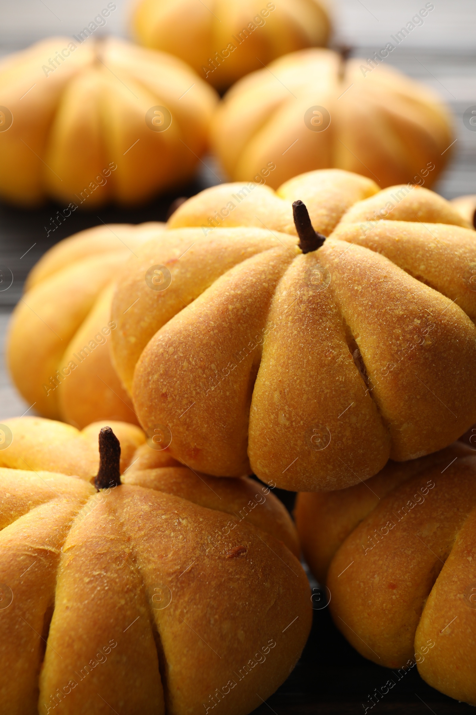 Photo of Pile of tasty pumpkin shaped buns on table, closeup