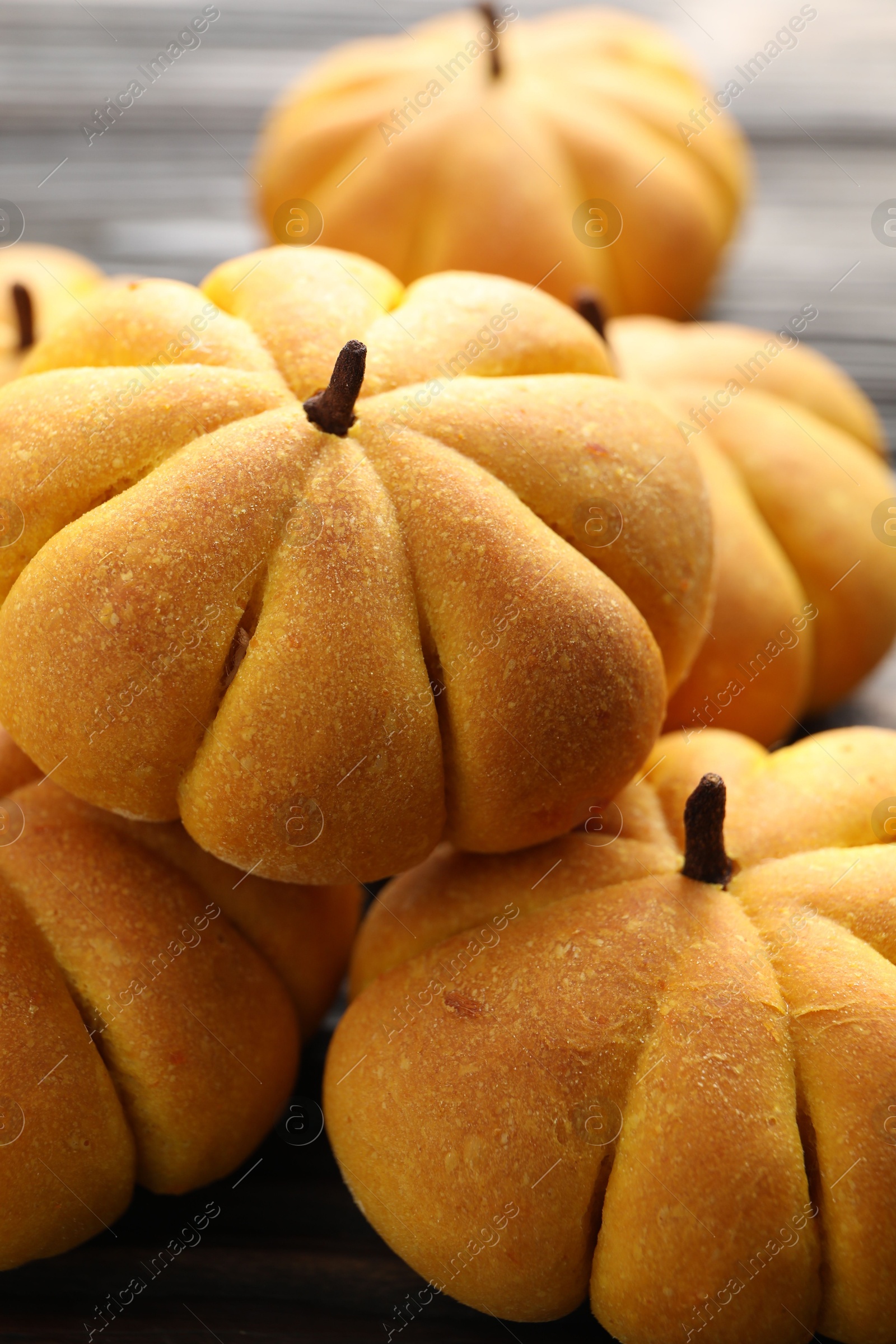 Photo of Pile of tasty pumpkin shaped buns on table, closeup