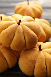 Photo of Pile of tasty pumpkin shaped buns on table, closeup