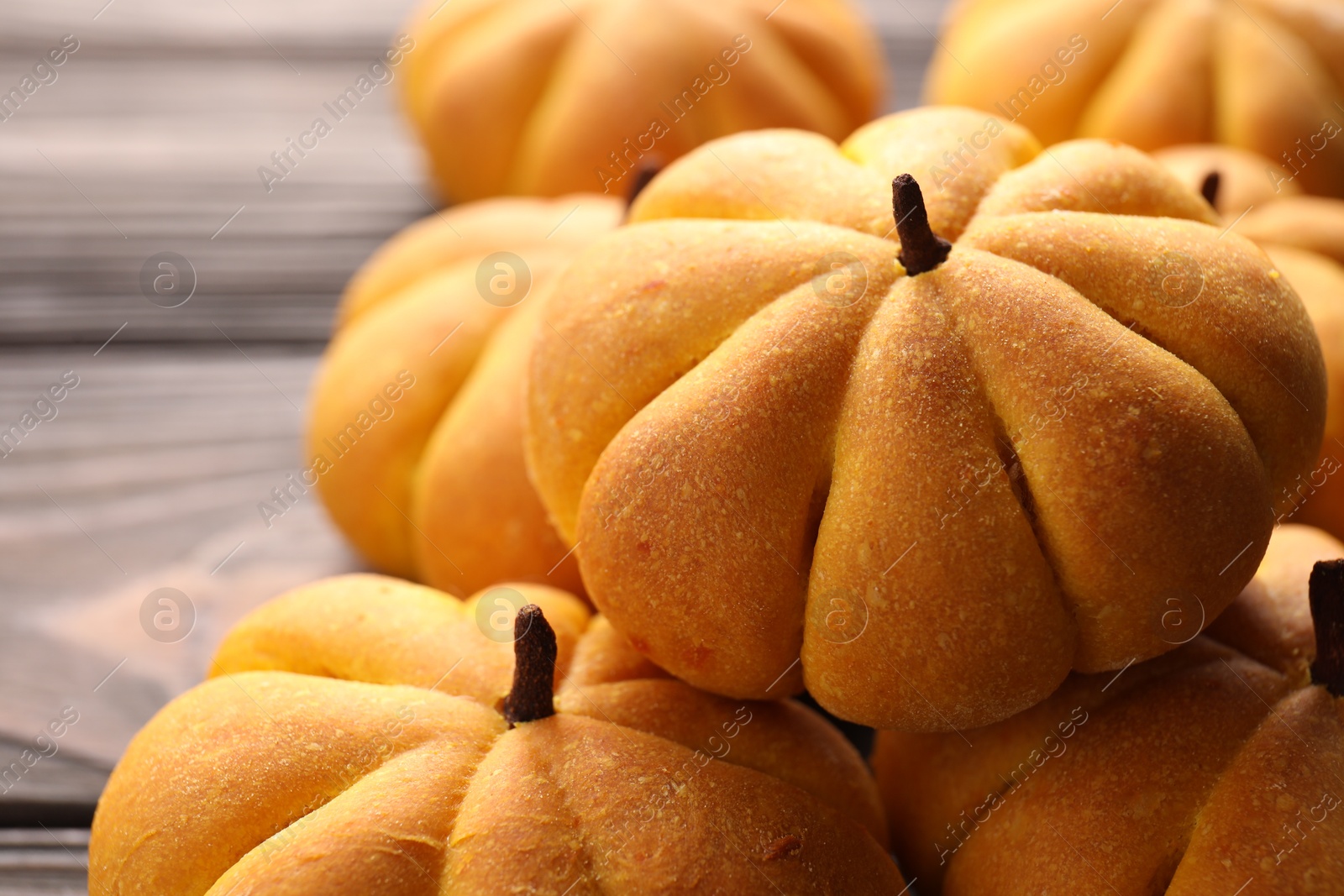 Photo of Pile of tasty pumpkin shaped buns on table, closeup