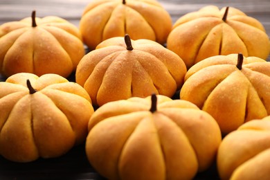 Photo of Pile of tasty pumpkin shaped buns on table, closeup