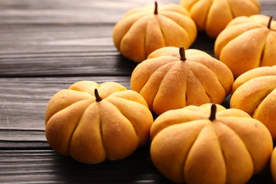 Photo of Tasty pumpkin shaped buns on wooden table, closeup