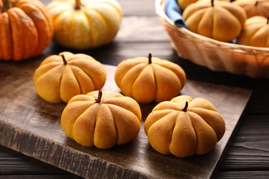 Photo of Tasty pumpkin shaped buns on wooden table, closeup