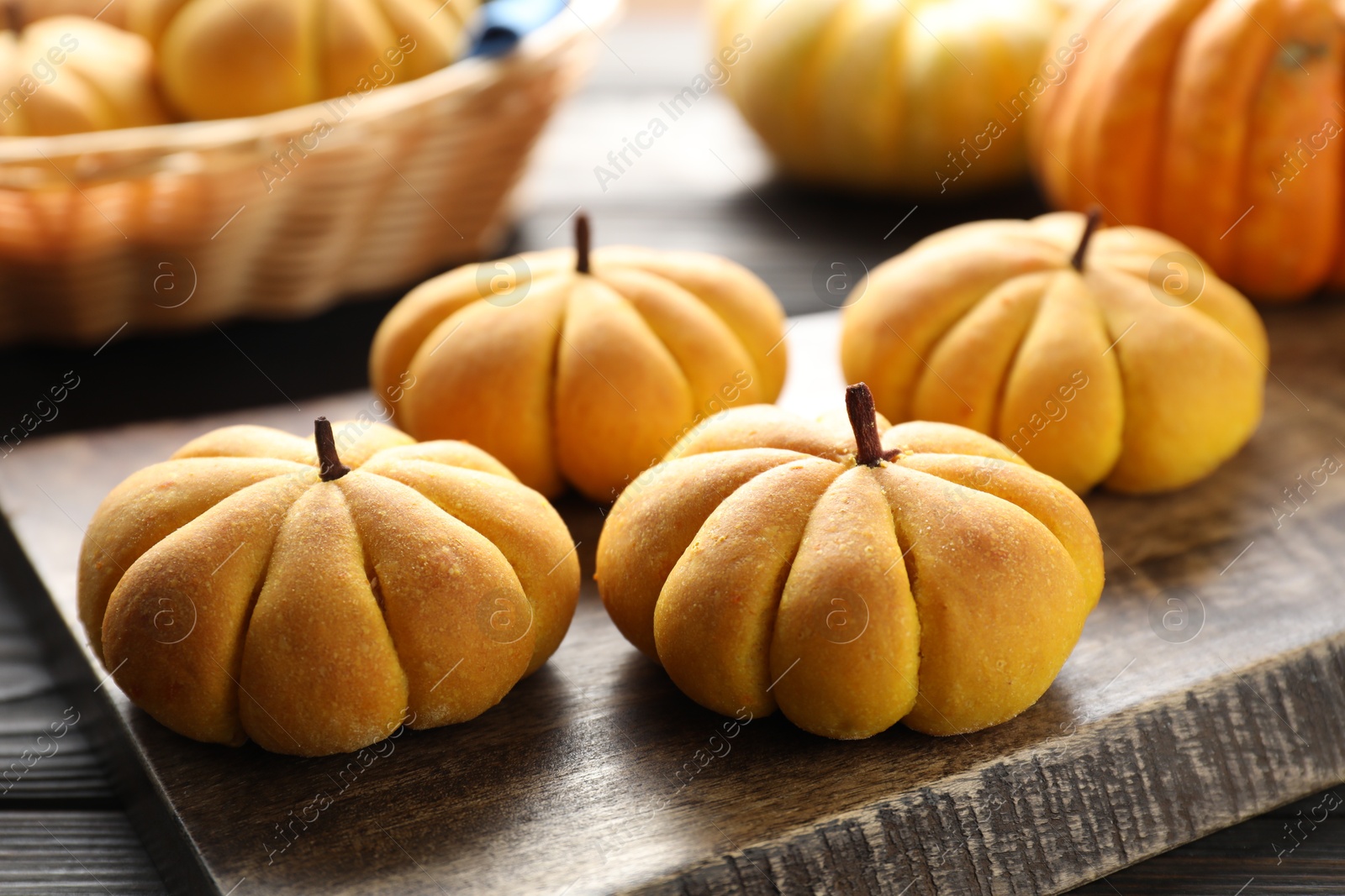 Photo of Tasty pumpkin shaped buns on wooden table, closeup