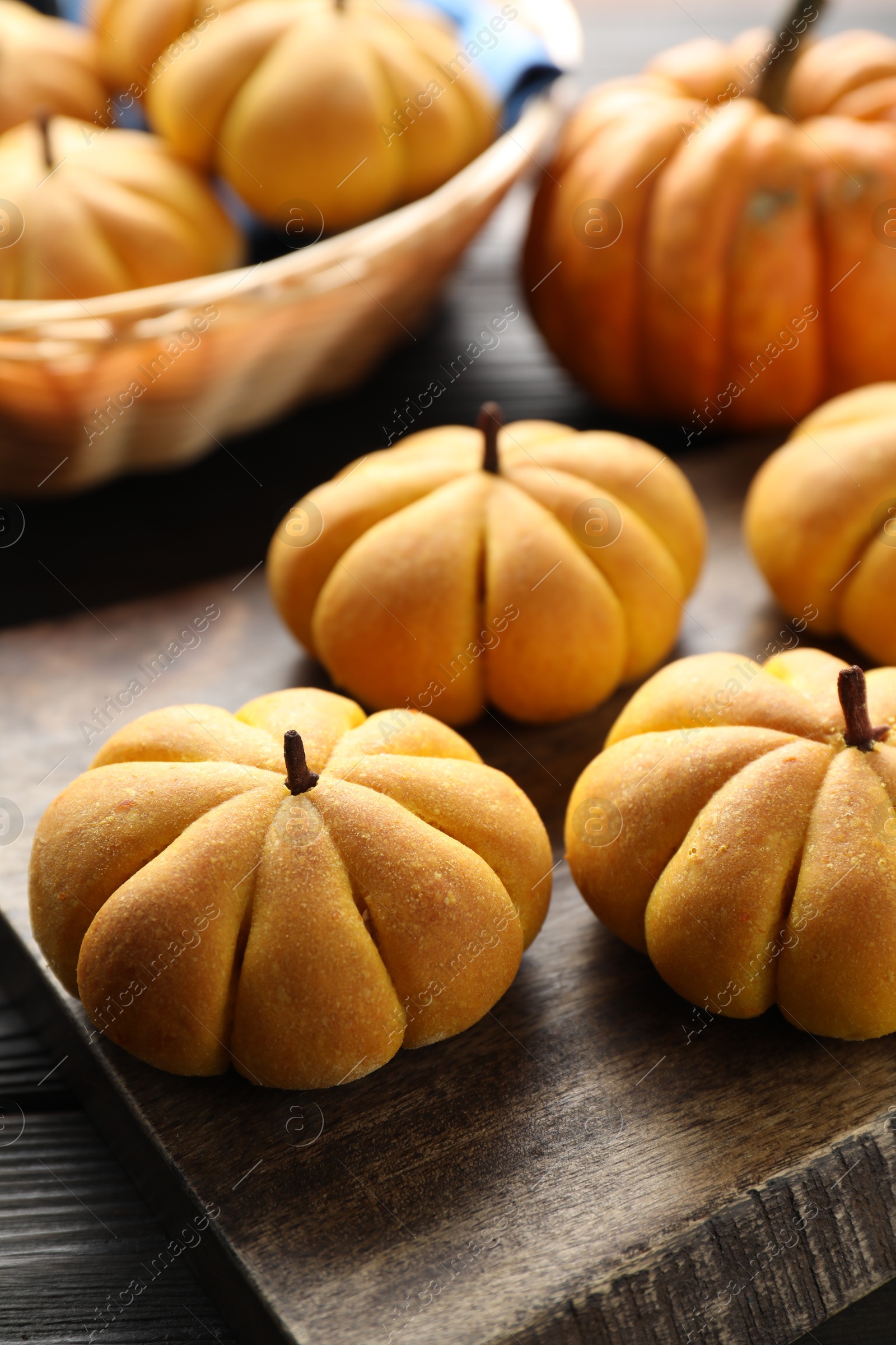 Photo of Tasty pumpkin shaped buns on wooden table, closeup